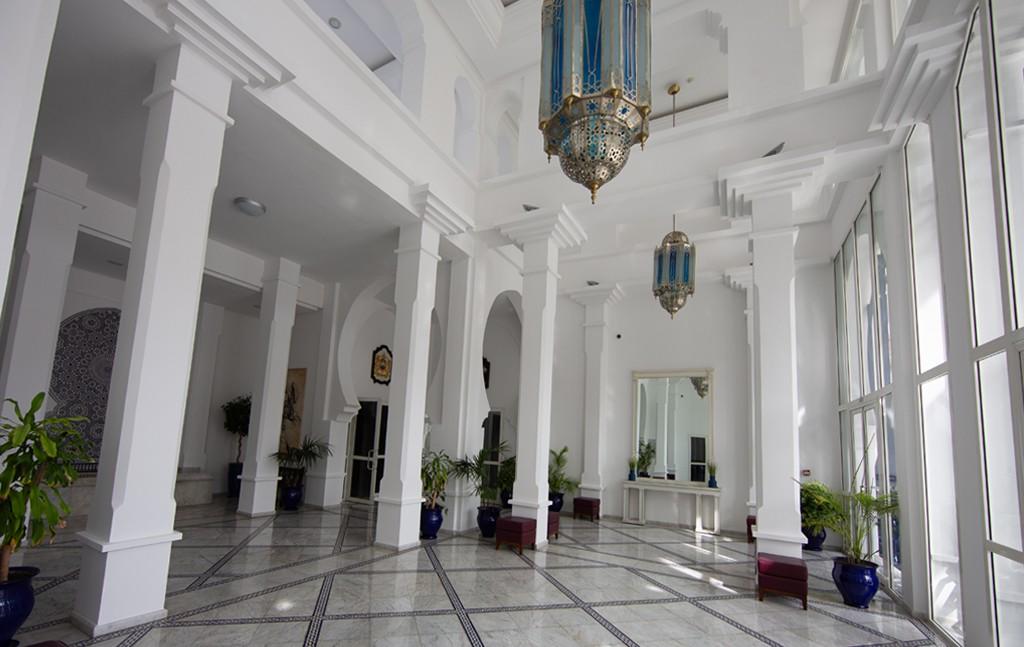 An interior room with white columns and blue and silver Moroccan lamps hanging from the ceiling